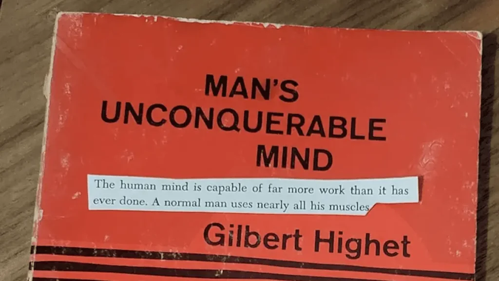 Man's Unconquerable Mind. Phrases of the paperback have been cut out with scissors and arranged on the red book cover. Here: 'The human mind is capable of far more work than it has ever done. A normal man uses nearly all his muscles...'