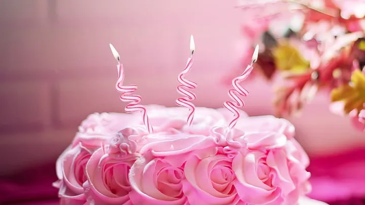 pink cake with rose frosting and three twisty candles