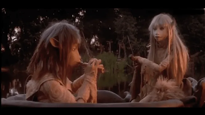 Jen the Gelfling plays the flute while Kira the Gelfling rows their river boat