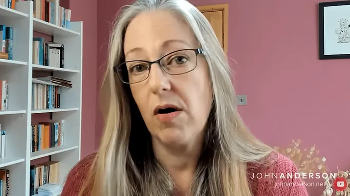 Helen Joyce is a white woman with long platinum hair and glasses. A still from the video interview.