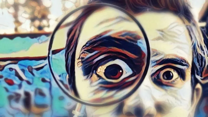 person looks through a magnifying glass, which makes one eye appear very big