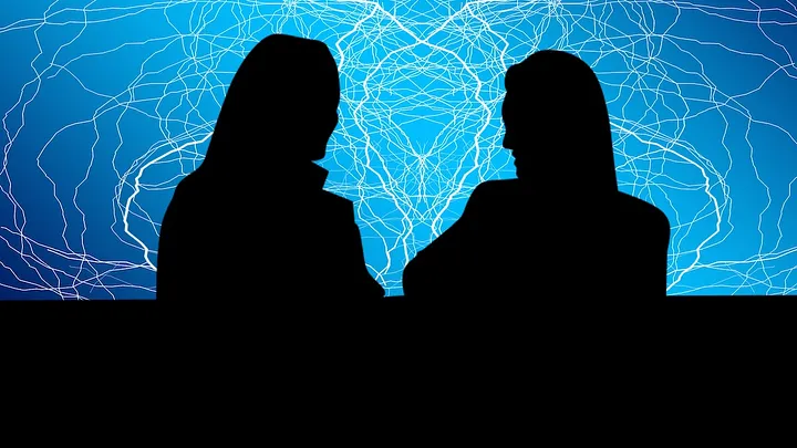 Silhouette of two women against an electric blue background.