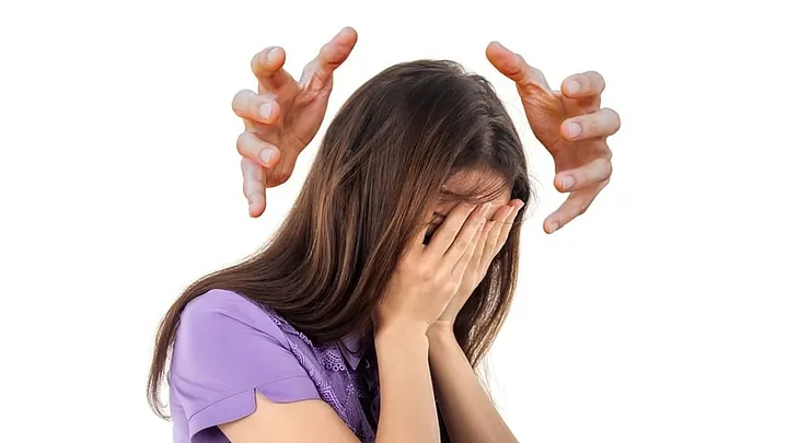 disembodied creepy hands reach around the head of a long-haired child in a purple short-sleeved shirt covering her face with her own hands