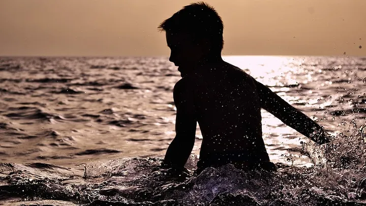 Silhouette of a child wading in the ocean