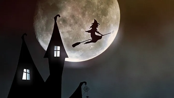 witch on a broomstick flies by a huge full moon