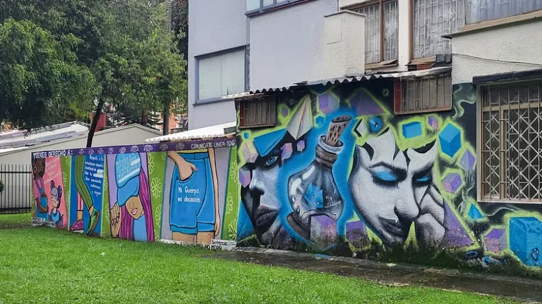 large residential building with a wall on which street artists painted murals. one side is a person with blue eyeshadow and a stoppered bottle of some potion. another side has a four-panel educational mural about reproductive rights.