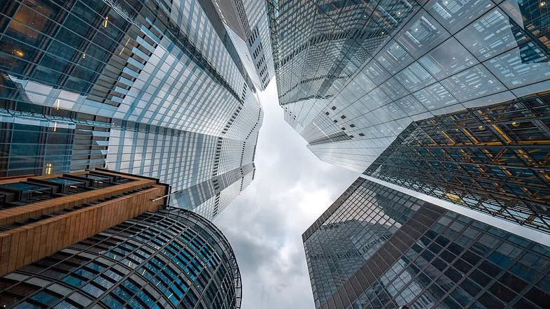 skyscrapers seen from the ground looking straight up. cool perspective. a little strip of sky.