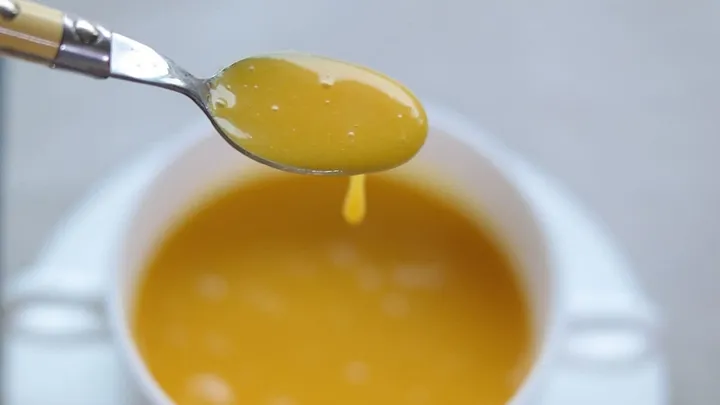 spoon of yellow soup from a cup