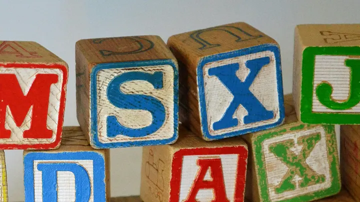 wooden letter blocks for a small child, etched and carved with letters. the two letters at the center are S and X.