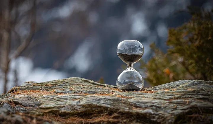 hourglass on a rock ledge in the wilderness