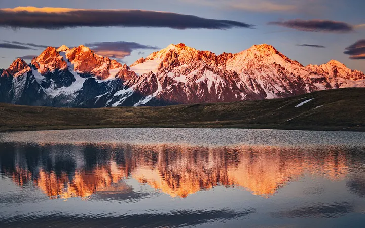 mountain range glowing orange and reflecting in a lake