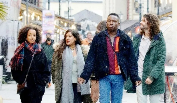 four young adults, dressed in casual, colorful clothes, walk on a city street