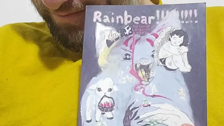 Tucker Lieberman wearing a bright yellow T-shirt and holding up a copy of Rainbear!!!!!!!!!
